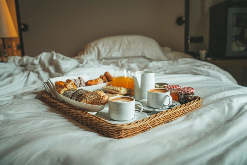 A tray of breakfast on a bed with white sheets