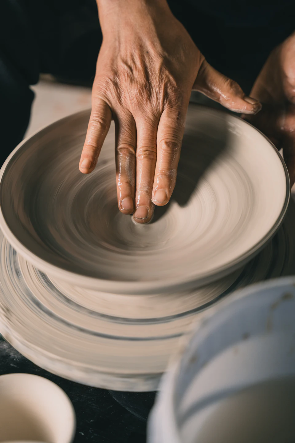 Hands shaping clay on a pottery wheel