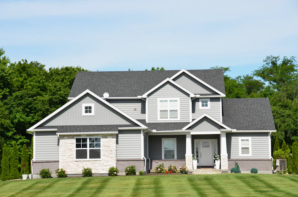A modern grey house with a green lawn and trees